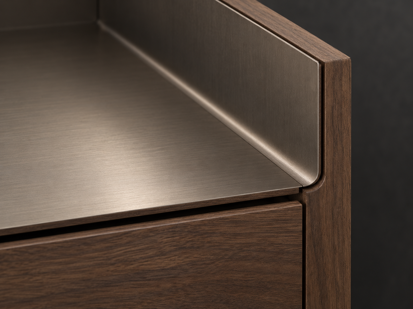 Close-up of brushed metal meeting smoked walnut at a finely detailed cabinet corner